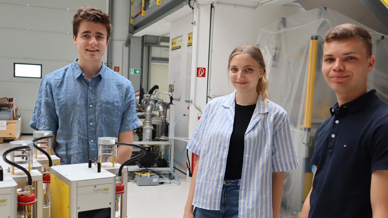 Three interns next to field calibration system in new Technical Innovation Center