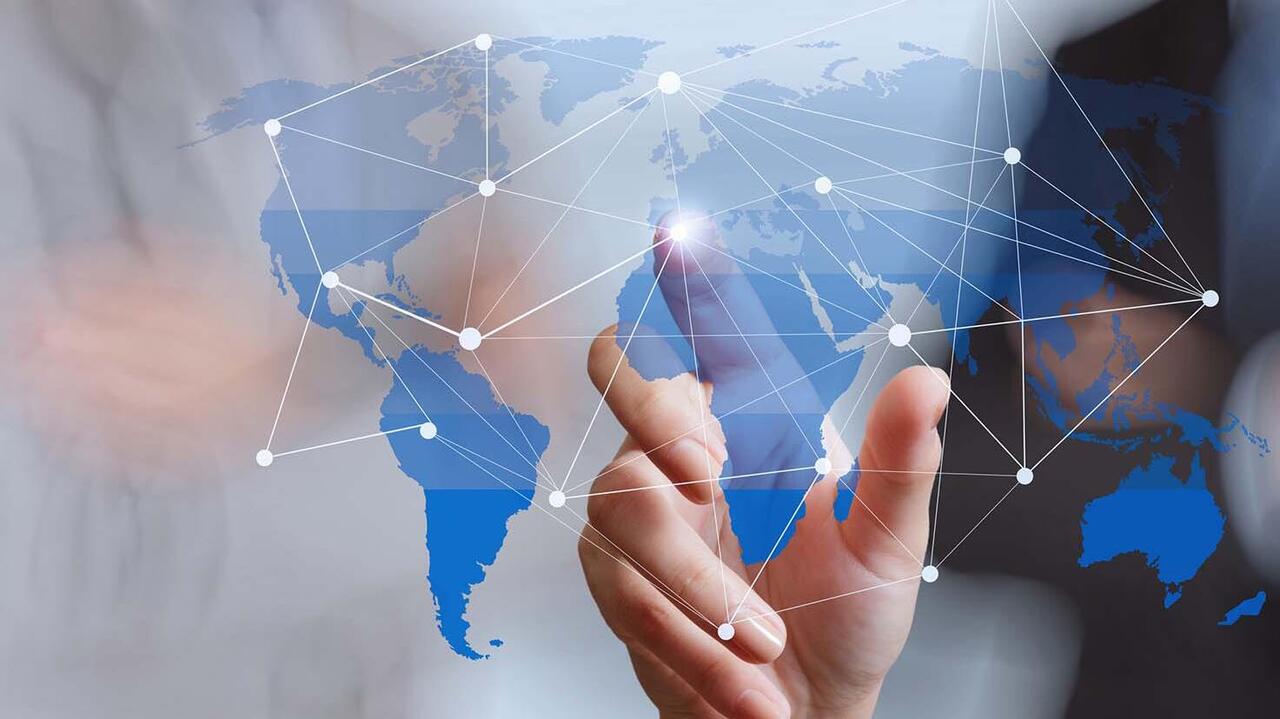 World map on glass, with a person standing in the background 