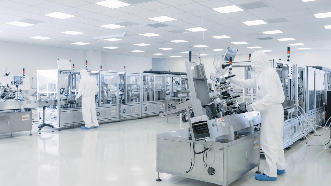 Production hall semiconductor research with scientists in protective equipment at machines 