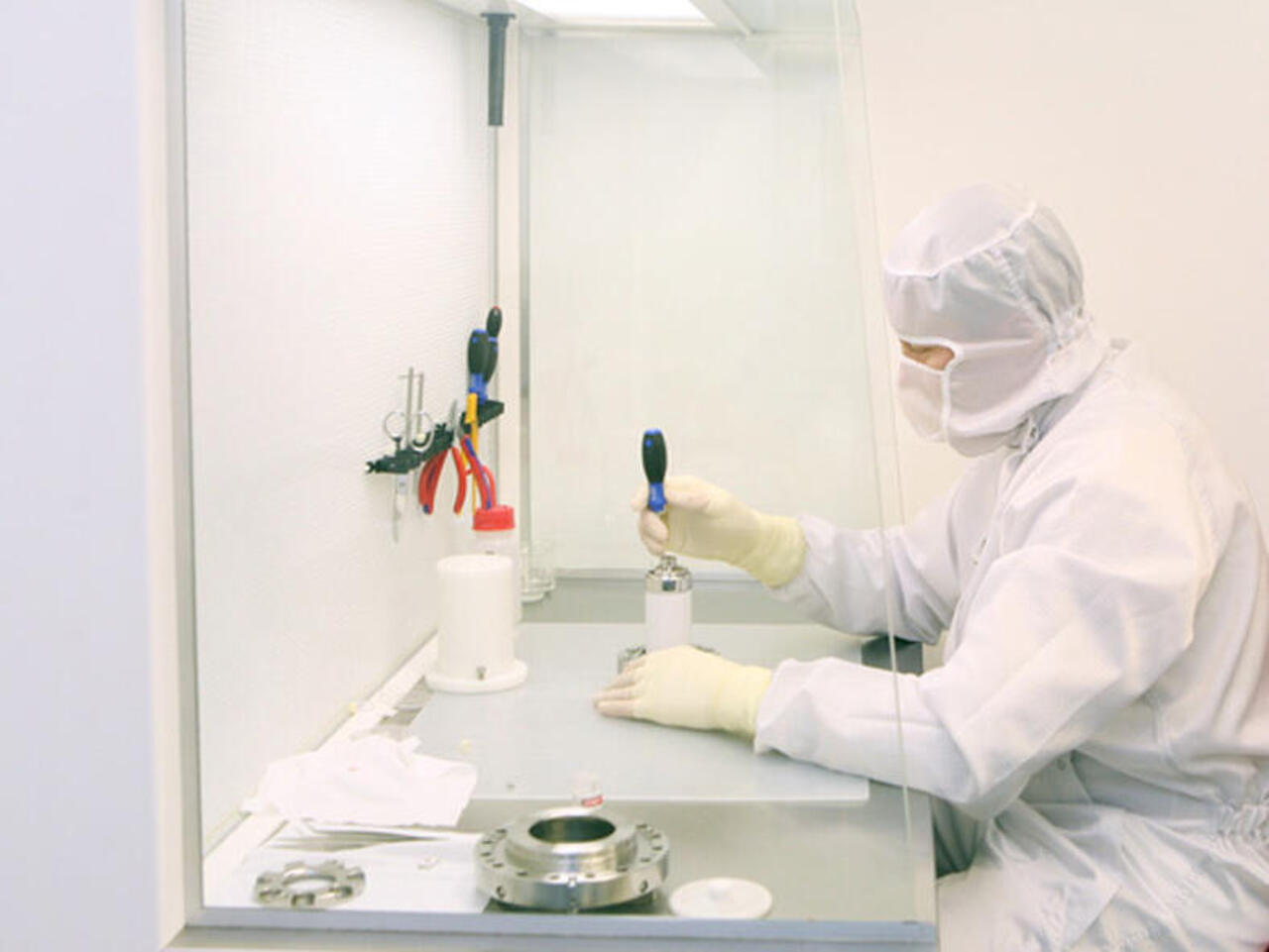 Safety workbench with laboratory technician in front of it in a protective suit working on a sample