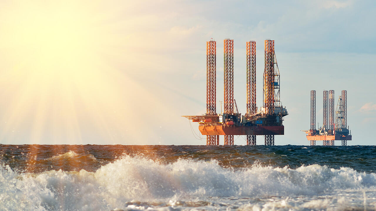 Drilling rigs in the sea with foaming spray in the foreground