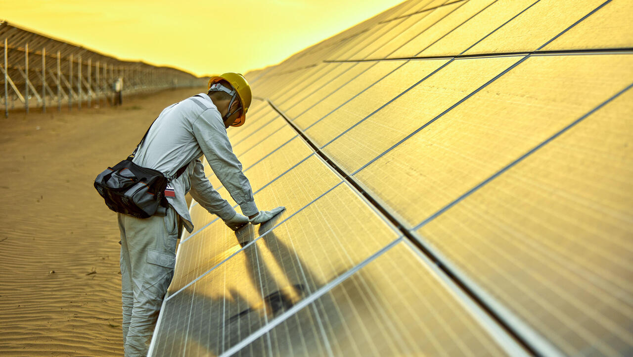 Engineer tests photovoltaic system in desert against yellow sky